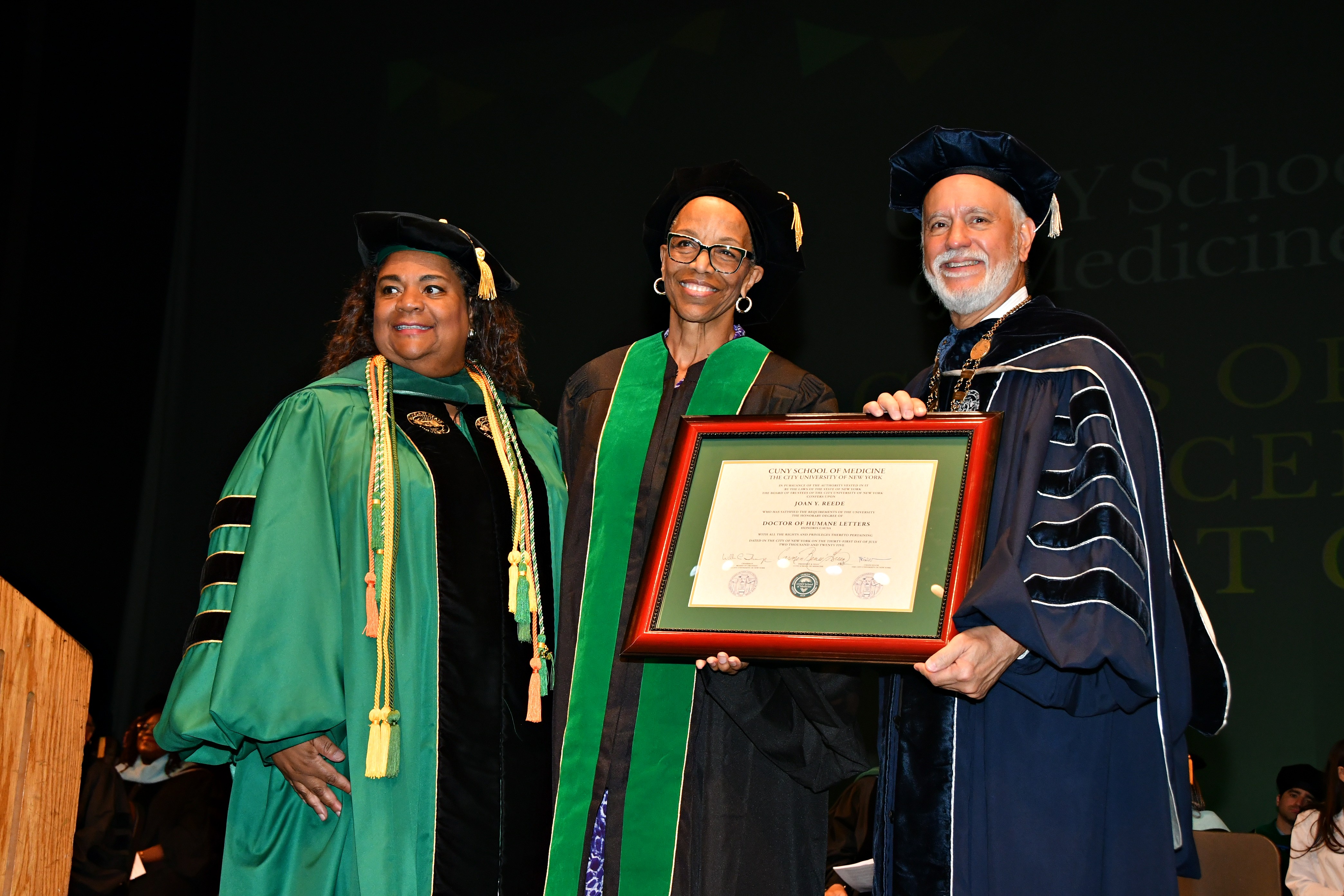 Joan Reede holds up her honorary degree alongside CUNY Chancellor Félix V. Matos Rodríguez and CUNY School of Medicine Dean Carmen Renée Green.