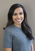 Mehedia is wearing a short-sleeve gray shirt. She has medium-length straight brown hair.
