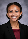 Meron is wearing a black blazer with maroon blouse.