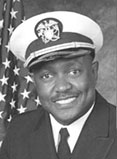 Philip is wearing a military cap and has an American flag in the background.