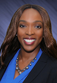 Shelly is smiling and wearing a blue blouse with a black blazer.
