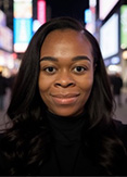 Emefah Loccoh is standing in the middle of Times Square in New York. She is wearing a black turtleneck.