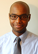 Jonathan Abraham is a bald man with glasses wearing a light gray shirt with a dark gray tie.