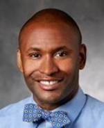 Dennis Spencer is a bald man wearing a blue shirt and blue patterned bowtie.