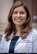 Diana Lopez is wearing a white doctor's coat and plaid dress.