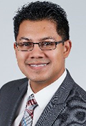George Molina is wearing a gray blazer, white shirt, and gray-red patterned tie.