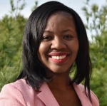 Hermioni Amonoo is standing outside. She is wearing a pink blazer.
