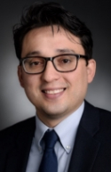 Jose F. Figueroa is wearing a black blazer, light blue shirt, and dark blue tie. 