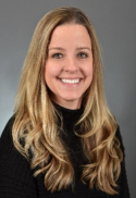 Marcella F. Luercio has long blonde hair. She is wearing a black turtleneck.