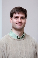  Ramiro Massol is wearing a beige sweater with a light green shirt underneath.