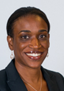 Richelle C. Charles is wearing a black blazer, necklaze, and earrings. She has short black hair.