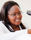 Selena Heman-Ackah Briggs is smiling while looking at a microscope that is mostly out of frame.