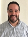 Steven Rodriguez is wearing a grid-patterned white shirt. He has short dark hair and facial hair.