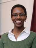 Mary Townsend is wearing a white shirt underneath a green sweater. She has cropped black hair.