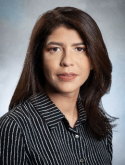 Ana Paula Abreu has long brown hair. She is wearing a striped black shirt.