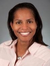 Natasha M. Archer is wearing a pink shirt and necklace. 