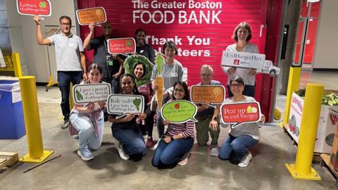 OCCE staff pose for a photo while holding produce-themed signs. 