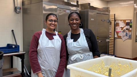Two OCCE staff members in the kitchen next to a container of egg salad.