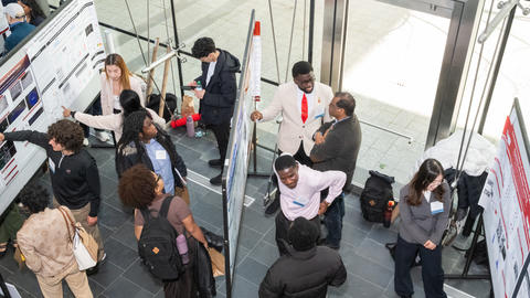 People gather around posters in the lobby of the Veritas Science Center.