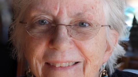 Anne Young has short white hair and is wearing frameless glasses.