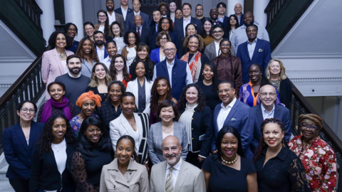 A group of Commonwealth Fund Fellowship alumni are standing on steps in the Waterhouse Room and smiling for a photo.