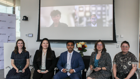 Recipients of the 2026 Dean's Community Service Award sit in a classroom in Countway Library. There is a projector screen behind them showing additional recipients.