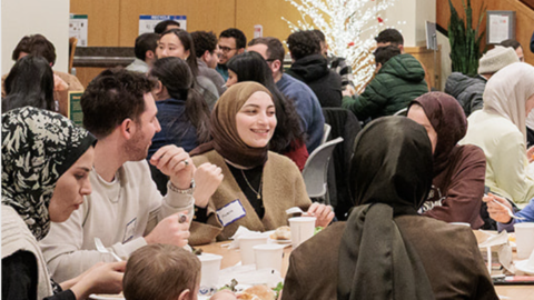 A group of students sit around a table of food and drinks in the Kresge Cafeteria.