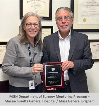 The MGH Surgery Department Mentoring Program leaders hold their award in front of a wall with many framed degrees.