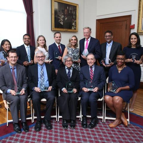 2026 Excellence in Mentoring Awards recipients line up for a photo in the Waterhouse Room. They are all holding their angular glass awards.