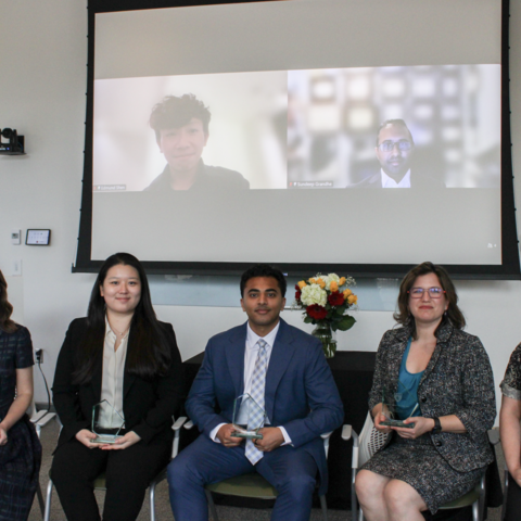 Recipients of the 2026 Dean's Community Service Award sit in a classroom in Countway Library. There is a projector screen behind them showing additional recipients.