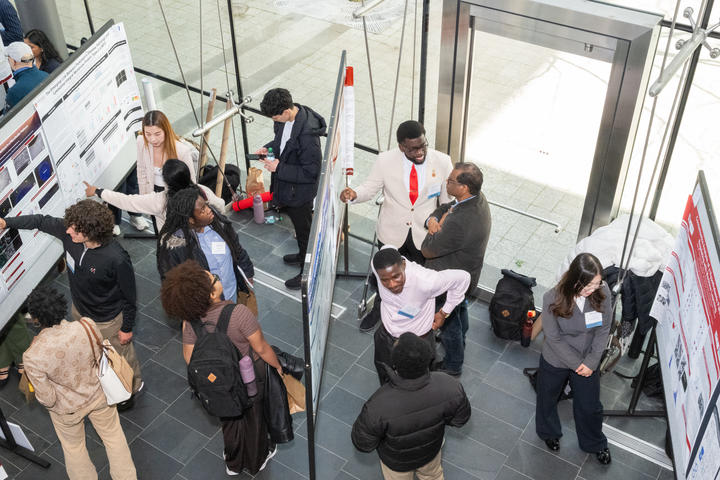 People gather around posters in the lobby of the Veritas Science Center.