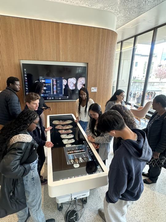 Randolph High School students surround the Anatomage Table at Countway Library. This operating-bed sized table provides highly accurate 3D visualizations of human anatomy. 