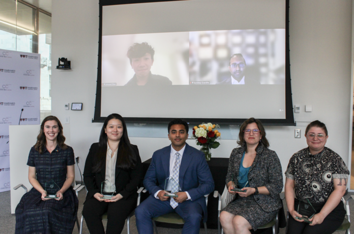 Recipients of the 2026 Dean's Community Service Award sit in a classroom in Countway Library. There is a projector screen behind them showing additional recipients.