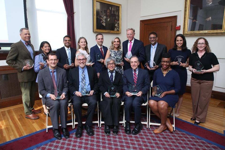 2026 Excellence in Mentoring Awards recipients line up for a photo in the Waterhouse Room. They are all holding their angular glass awards.