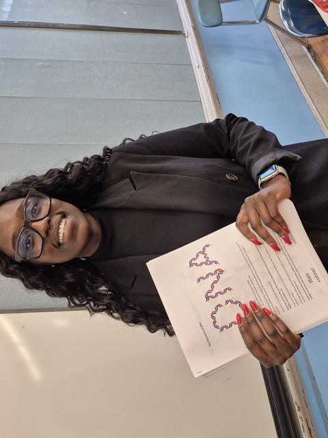 Bernie Owusu-Yaw is holding a sheet of paper with the word "DNA" on it.