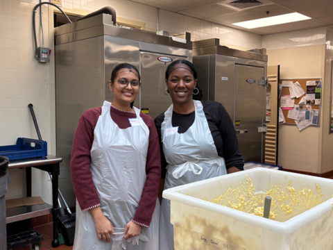 Two OCCE staff members in the kitchen next to a container of egg salad.