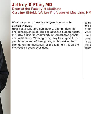 Jeffrey Flier is wearing a black striped blazer, white shirt, and turquoise tie. His hands are clasped in front of him.
