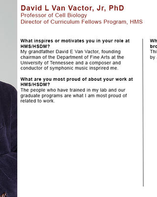 David Van Vactor is holding a small white microscope. He is wearing a dark corduroy blazer and orange shirt.