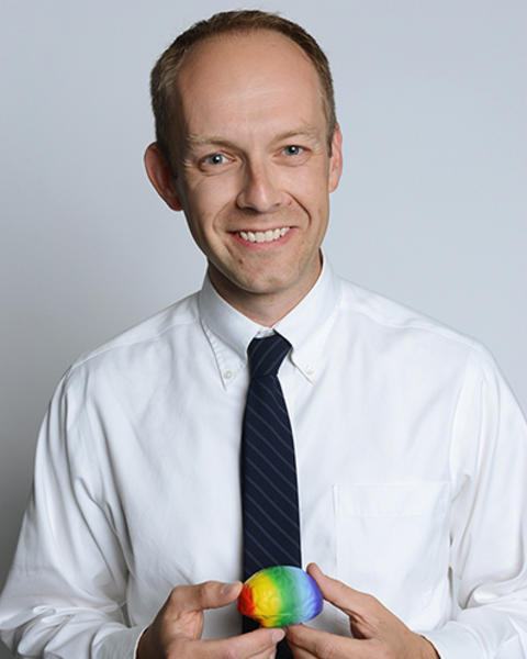 Christopher AhnAllen holds a multicolor brain model in both his hands.