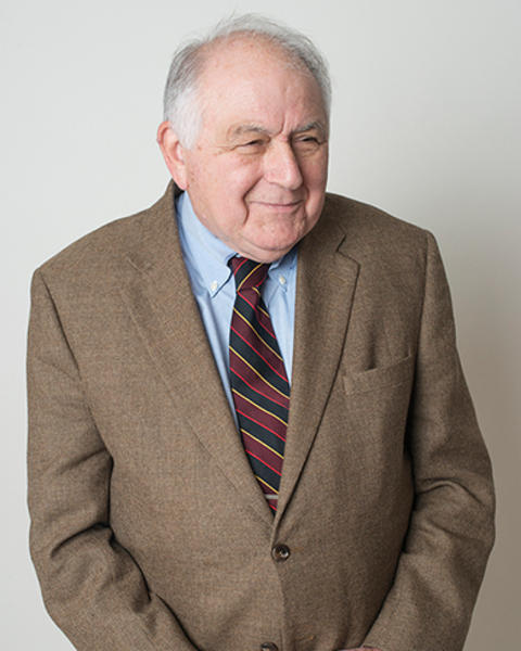 Ronald Arky clasps his hands while he looks off-camera with a small smile on his face.