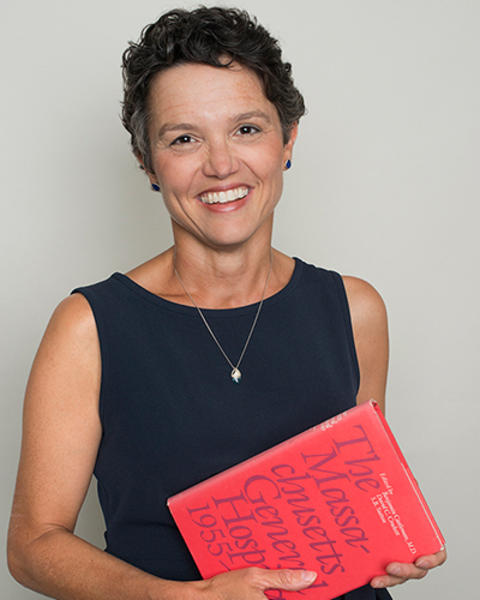 Katrina Armstrong holds a red book about the history of MGH from 1955 to 1980.
