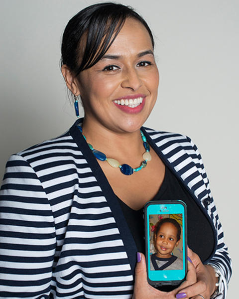Franceny Bedoya is holding up a phone with a photo of her son on it.