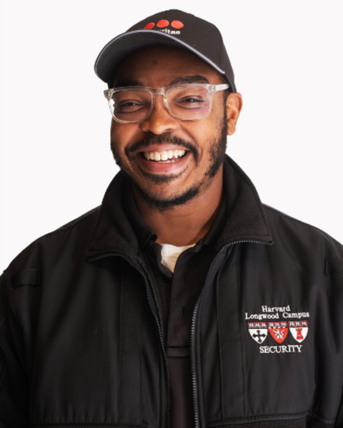 James Pulley is wearing a black Securitas hat and black Harvard Longwood Campus Secruity zip-up jacket. 