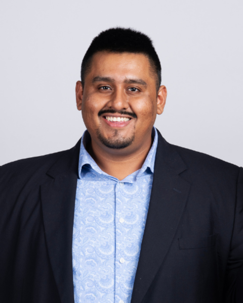 Harpreet Singh is wearing a black blazer and patterned blue shirt. 