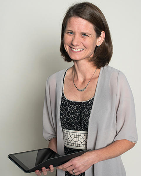 Kristin Bittinger is holding a small iPad with a black foldable case. 
