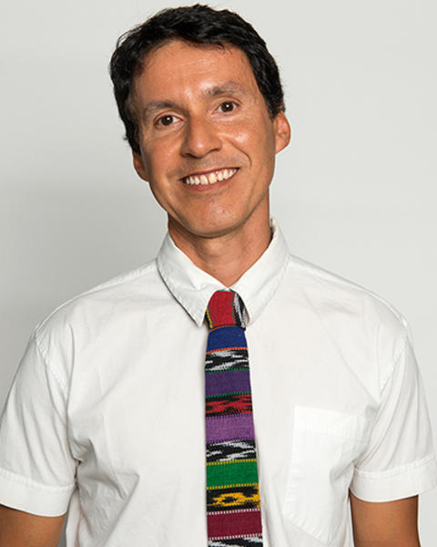 Manuel Chinchilla is wearing a short-sleeved white button-down with a colorful woven tie.