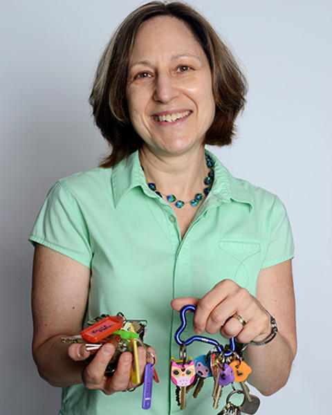 Karen Easley is wearing a seafoam green shirt and is holding up multiple carabiners of colorful keys.