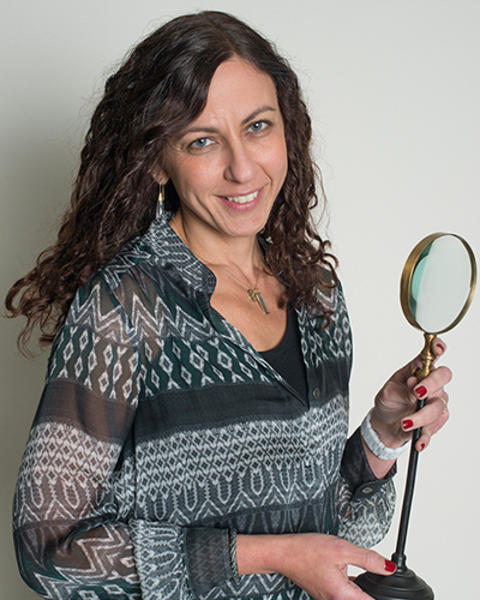 Galit Lahav is holding up a magnifying glass on a stand.