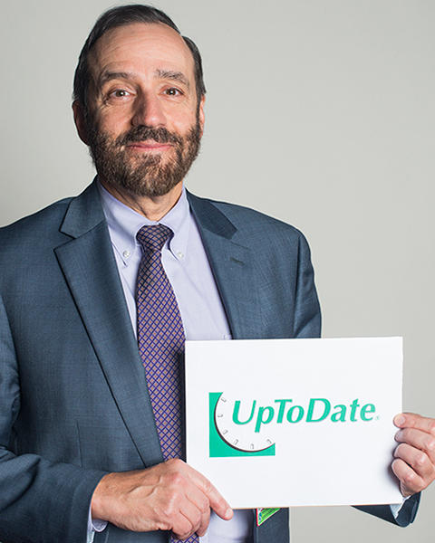 Robert Barbieri is holding a white paper with the UpToDate logo on it.