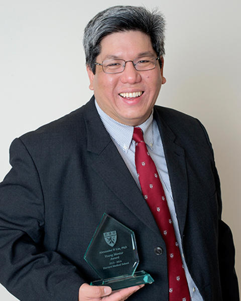 Alexander Link is holding a glass Young Mentor Award from 2014 that he received.